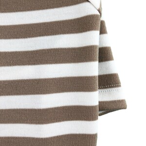 May include: Close-up of a brown and white striped fabric. The fabric is folded over on itself, showing the stitching on the edge.