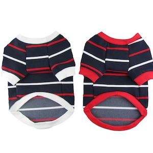 Puede incluir: Dos camisas a rayas para perros, una con ribete blanco y otra con ribete rojo. Ambas camisas tienen rayas azul marino y rojas.
