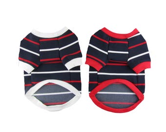 May include: Two striped dog shirts, one with a white trim and one with a red trim. Both shirts have navy blue and red stripes.