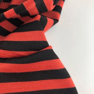 May include: Close-up of red and black striped fabric. The fabric is soft and has a subtle texture.