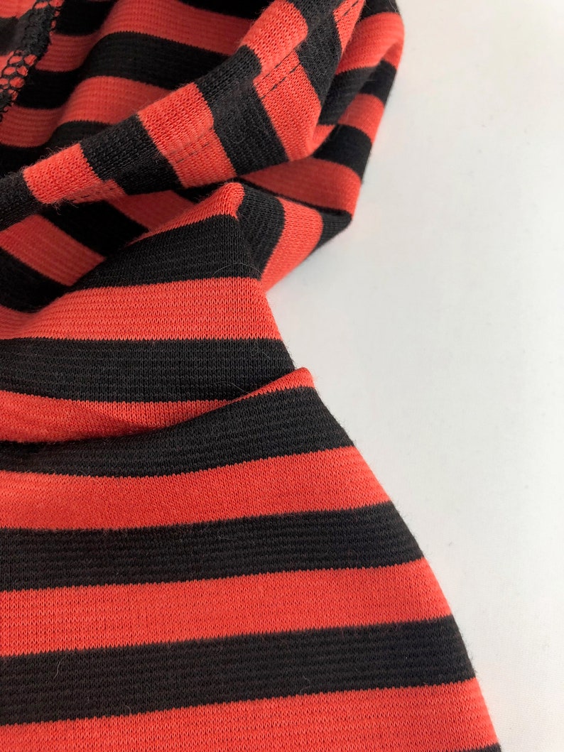 May include: Close-up of red and black striped fabric. The fabric is soft and has a subtle texture.