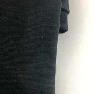 Puede incluir: Primer plano de una tela de punto negra con una superficie texturizada.