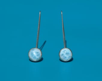 Könnte beinhalten: Ein Paar silberne Ohrringe mit hellblauen Edelstein-Akzenten. Die Ohrringe haben ein schlichtes, minimalistisches Design.