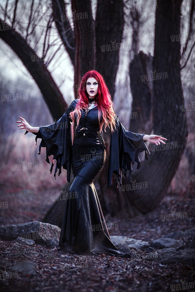 Model wearing gothic black gown in misty forest