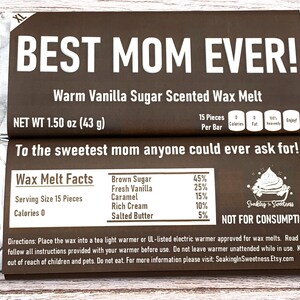 May include: A brown and silver foil-wrapped bar of wax melts with the text "BEST MOM EVER!" and "Warm Vanilla Sugar Scented Wax Melt". The bar is labeled with "NET WT 1.50 oz (43 g)" and "To the sweetest mom anyone could ever ask for!" The back of the bar lists the wax melt facts, including the ingredients and percentages, and a warning that the product is "NOT FOR CONSUMPTION".