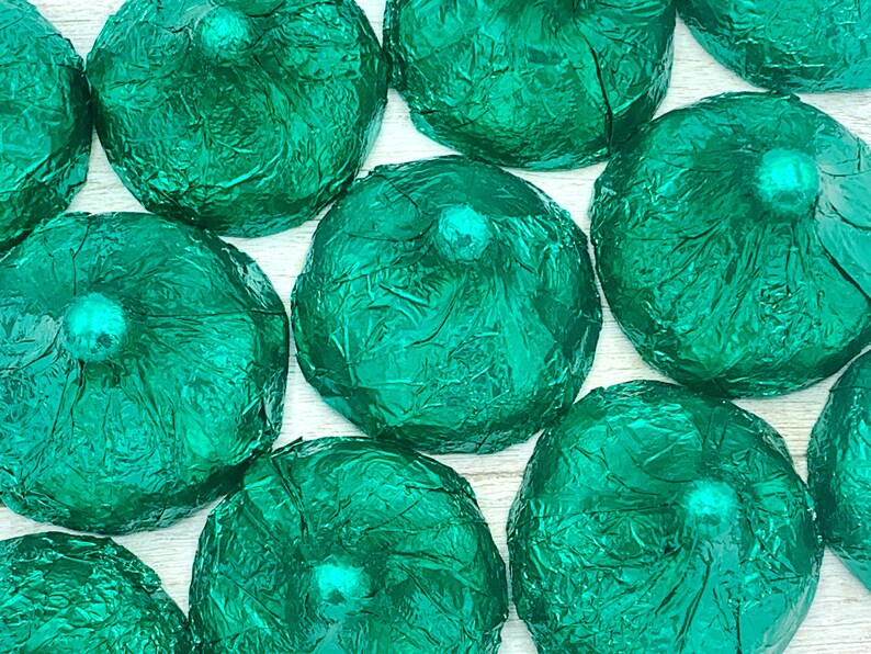 May include: A group of green foil-wrapped chocolate candies. The candies are arranged in a close-up view, showing the texture of the foil.
