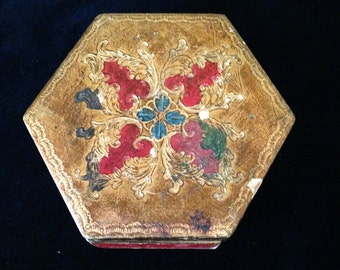 May include: A hexagonal wooden box with a gold painted surface and a red, green, and blue floral design. The box has a red velvet lining.