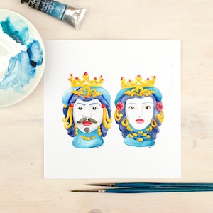 May include: Watercolor painting of two ceramic heads with crowns, one blue and one yellow, on a white background.