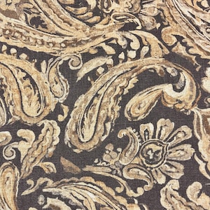 May include: A brown and beige paisley patterned fabric with a textured surface.