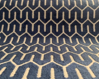 May include: Close-up of a blue fabric with a repeating geometric pattern. The pattern consists of white, interconnected shapes against a dark blue background. The fabric has a soft, textured appearance.