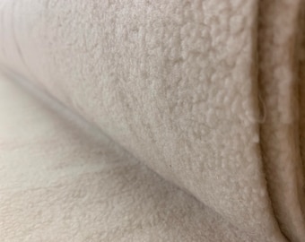 May include: Close-up of a white, fluffy fabric rolled up. The fabric has a soft, textured surface.