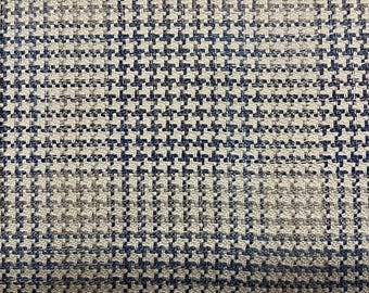 May include: A close-up of a fabric with a blue and beige houndstooth pattern. The fabric has a textured surface.
