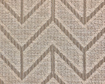 May include: Close-up of a textured fabric with a repeating chevron pattern. The fabric has a neutral color palette, with a light beige background and darker beige chevron stripes. The design creates a sense of depth and visual interest.