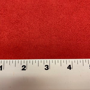 May include: Close-up of a red fabric swatch with a textured surface. A ruler is placed at the bottom of the image with markings from 1 to 5 inches.