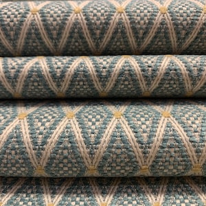 May include: Close-up of a blue and white patterned fabric with a geometric design. The fabric has a subtle sheen and a textured surface.