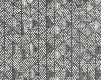 May include: A close-up of a white fabric with a repeating geometric pattern of dark blue diamonds and lines.