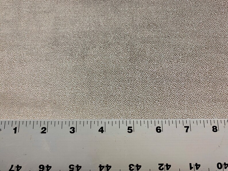 May include: Close-up of a white fabric with a textured surface. A ruler is placed at the bottom of the image with markings from 1 to 8 inches.