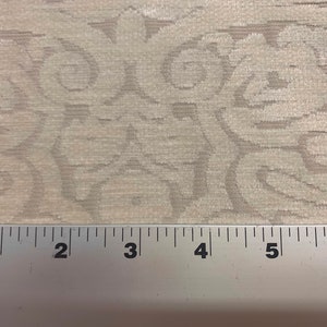 May include: Close-up of a white fabric with a subtle embossed pattern. A ruler is placed at the bottom of the image, showing measurements in inches.