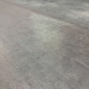 May include: Close-up of a textured, gray surface with a subtle sheen. The surface has a fine, grainy texture.