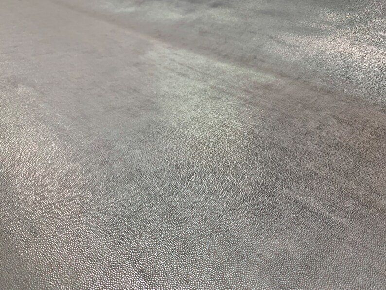 May include: Close-up of a textured, gray surface with a subtle sheen. The surface has a fine, grainy texture.