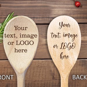 May include: Two wooden spoons with the text "Your text, image or LOGO here" on a wooden background. One spoon is labelled "FRONT" and the other "BACK". Rosemary sprigs and red berries are also visible.