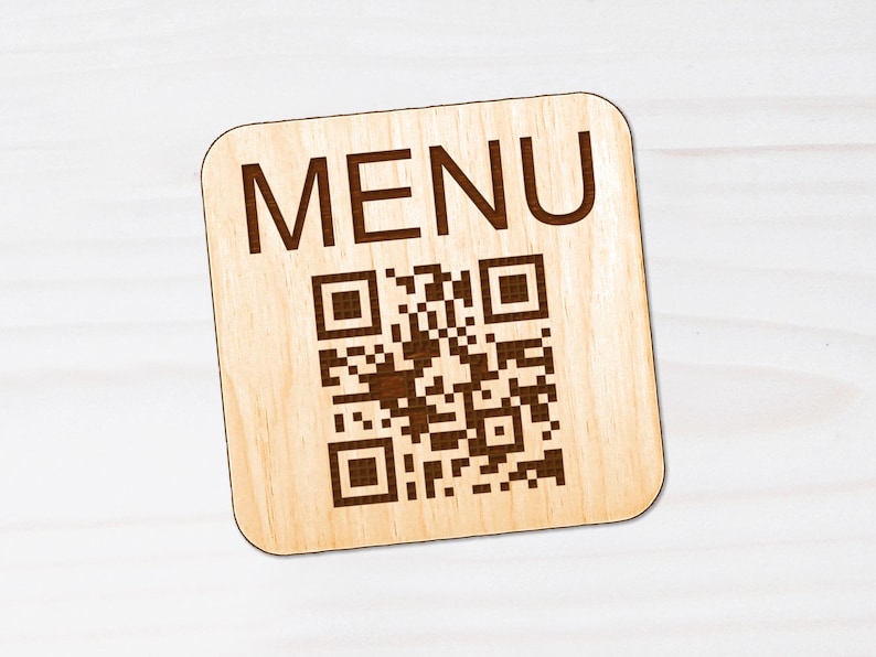 Puede incluir: Un letrero cuadrado de madera clara con esquinas redondeadas que presenta la palabra MENU en letras may&uacute;sculas de color marr&oacute;n oscuro en la parte superior y un c&oacute;digo QR marr&oacute;n oscuro impreso sobre la madera.