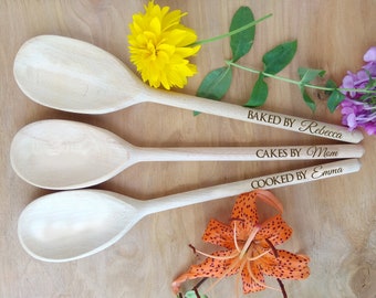 May include: Three wooden spoons with engraved text. The top spoon reads "Baked by Rebecca", the middle spoon reads "Cakes by Mom", and the bottom spoon reads "Cooked by Emma".