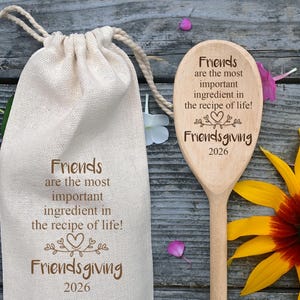 以下が含まれることがあります： 「Friends are the most important ingredient in the recipe of life! Friendsgiving 2026」の文字が入ったベージュの巾着袋と木のスプーン。 黄色と茶色のヒマワリが背景にあります。