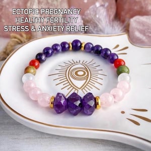 May include: A bracelet featuring amethyst and rose quartz beads, with gold-coloured spacers. The bracelet rests on a white plate with a gold eye design. Text on the image reads "ECTOPIC PREGNANCY HEALTHY FERTILITY STRESS & ANXIETY RELIEF."