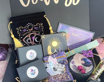 May include: A black gift box containing a velvet pouch with gold print, three black boxes with circular stickers, a square card with gold sun art, a purple card with text, a sticker reading Don't be afraid to say no, and a black candle with crystals.