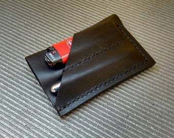 May include: A black leather wallet with three slots for cards or cash. A red lighter with the word "Clicker" is in the wallet.