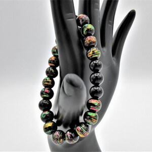 May include: A black beaded bracelet with iridescent green, red, and gold accents.