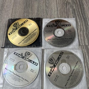 May include: Four CDs from The Dead's Wave That Flag Summer Tour 2004. The CDs are in clear plastic sleeves. The text on the CDs includes the band name, tour name, and the date and location of the concert.