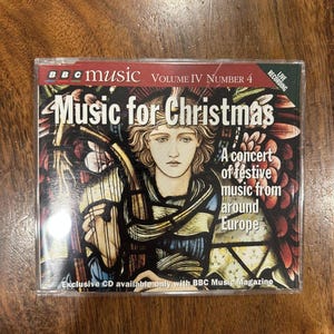 Op de afbeelding: Een cd-hoesje voor "Music for Christmas" van BBC Music. De cover toont een illustratie van een vrouw met een harp, met de tekst "Een concert van feestelijke muziek uit Europa". De cd is Volume IV nummer 4.