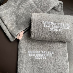 May include: Two grey towels with white embroidery. The top towel has the text "GEORGIA TAYLOR 61st SHEFFIELD SCOUTS". The bottom towel has the same text.