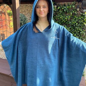 May include: A blue fleece hooded poncho featuring an embroidered white trefoil logo and the text "Rosin 3rd Frame Guides" on the upper chest. The garment has a wide, loose-fitting silhouette with an attached hood and long, open sides.