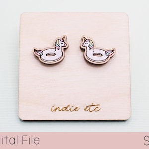 May include: Two wooden unicorn float earrings with pastel rainbow manes and tails. The earrings are displayed on a light wood square with the text "indie etc" etched on the bottom. The words "Digital File" and "SVG" are also present.