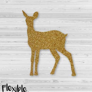 May include: A gold glitter deer silhouette. The deer is standing with its head turned slightly to the left. The background is a white wood grain pattern. The text "Flexible designs" is in the lower left corner.