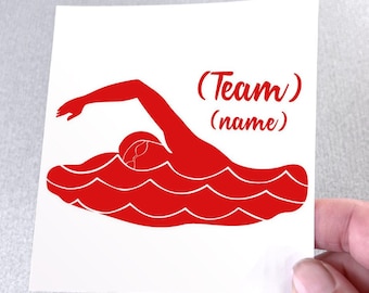 May include: A square white decal featuring a red graphic of a swimmer performing a freestyle stroke in wavy water. The text (Team) and (name) is printed in red script font above the swimmer, indicating a customizable area for team identification.