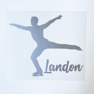 May include: A silver-colored vinyl decal featuring the silhouette of a figure skater in a gliding pose with one leg extended backward and arms outstretched. The name Landon is printed in a cursive script font in the same silver color below.