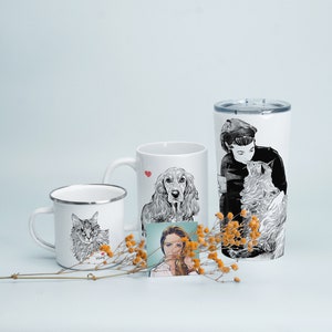 May include: Three white mugs with black and white illustrations of a cat, a dog, and a person with a cat. The mugs are on a white surface with dried flowers.