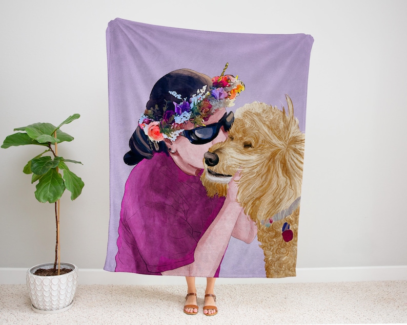 K&ouml;nnte beinhalten: Eine lilafarbene Fleece-Decke mit einer Aquarell-Illustration einer Person, die eine Blumenkrone und eine Sonnenbrille tr&auml;gt und einen Goldendoodle-Hund k&uuml;sst.