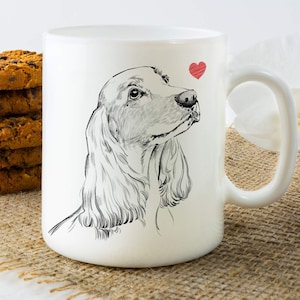 May include: White ceramic coffee mug with a black and white illustration of a cocker spaniel dog looking to the right. A small red heart is above the dog's head.