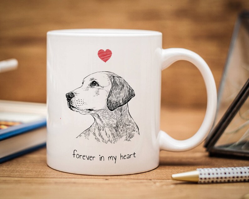 May include: White ceramic mug with a black and white illustration of a dog's head and the text "forever in my heart". A red heart is above the dog's head.