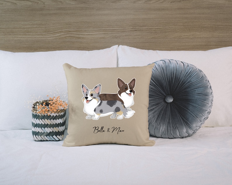 May include: Beige pillow with a cartoon illustration of two corgis, one blue and white and one brown and white. The text "Bella & Max" is printed below the dogs.