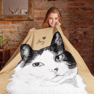 Puede incluir: Una manta de forro polar de color beige con una ilustraci&oacute;n en blanco y negro de un gato. El nombre del gato, "Joey", est&aacute; escrito en la manta con un coraz&oacute;n.
