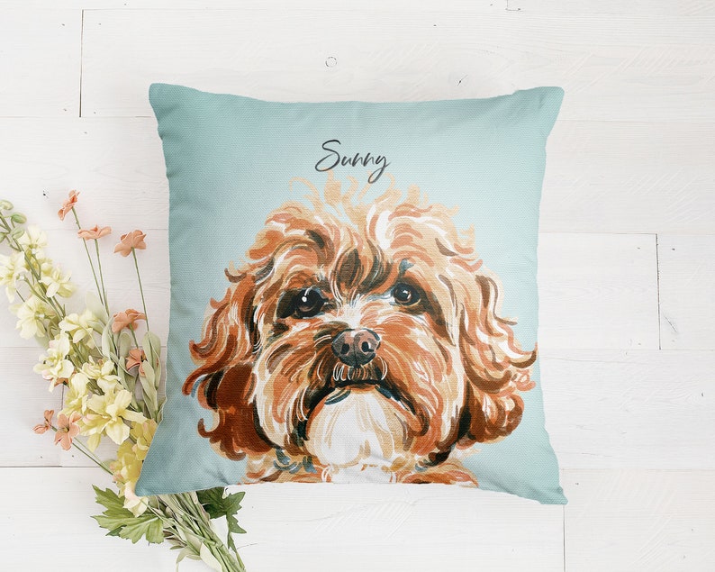 May include: A light blue throw pillow with a hand-painted illustration of a brown and white dog. The dog's name, "Sunny", is written in cursive on the pillow.