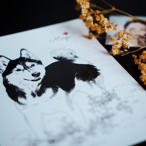 May include: A black and white drawing of a husky dog on a white card with the name "Maya" written in cursive. The card is surrounded by dried flowers.