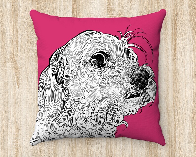May include: A pink pillow with a black and white line drawing of a dog's head. The dog is looking to the right and has a fluffy, curly coat.