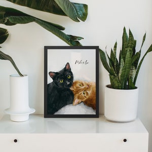 K&ouml;nnte beinhalten: Gerahmtes Bild von zwei Katzen, eine schwarze und eine orange, mit dem Text "Milo & Leo" dar&uuml;ber.